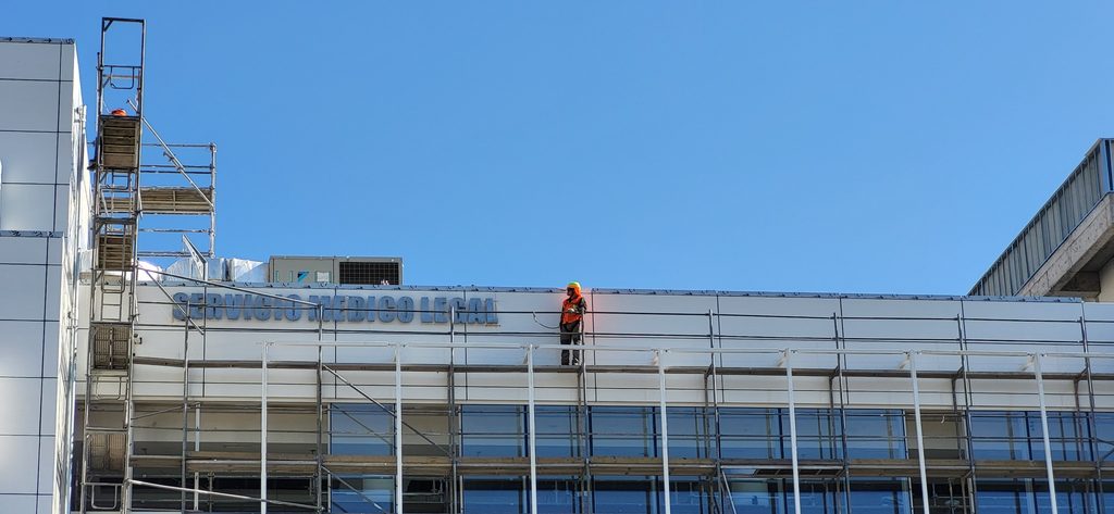 Instalación de letras volumétricas de acero inoxidable con acabado metálico natural en fachada de edificio en Santiago de Chile.